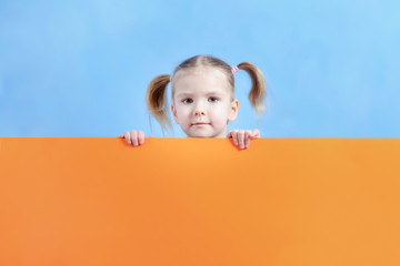 Layout with place for text on an orange background. Behind this baby with blond hair. Pretty little girl.