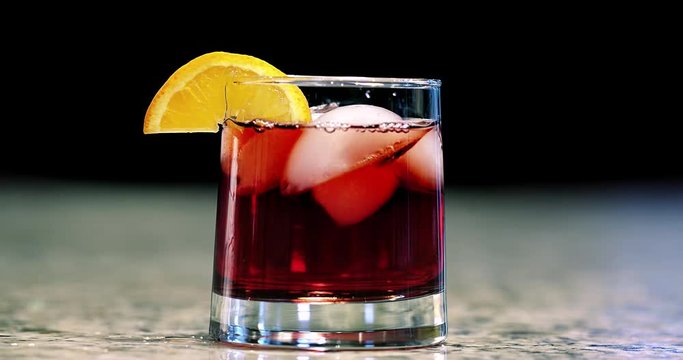 Close up of hand garnishing a mixed cocktail with an orange