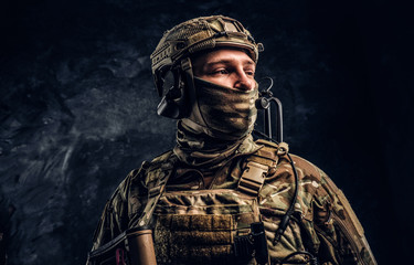 Modern special forces soldier in camouflage uniform looking sideways. Studio photo against a dark...