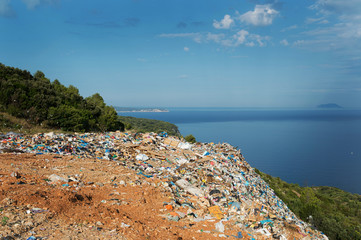 Piles of waste at landfill next to sea. Waste management, ecology, enviromental issues concept