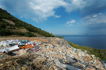 Piles of waste at landfill next to sea. Waste management, ecology, enviromental issues concept
