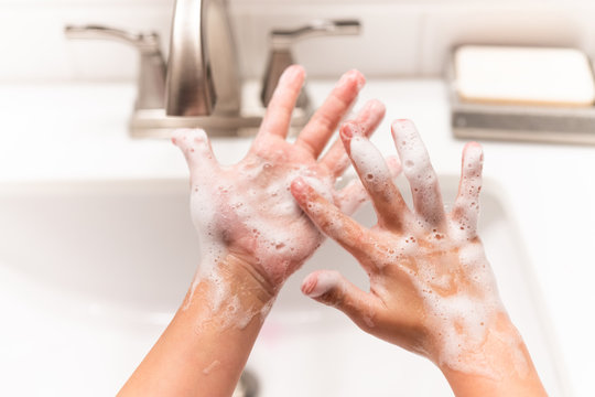 Close up of child washing hands over sink