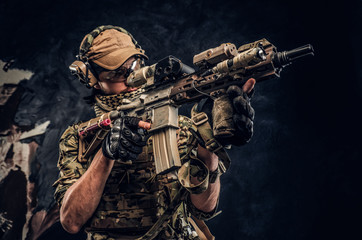 Special forces soldier in protective uniform holding an assault rifle and aim at the enemy. Studio...
