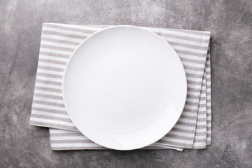 Empty plate with striped napkin on gray stone background. Top view.