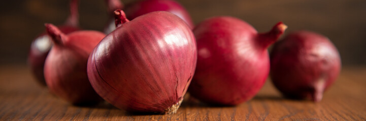 Fresh purple onions on dark wooden background.