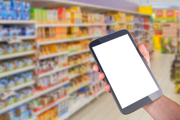 hand holding tablet with blank screen in front of goods shelfs in supermarket