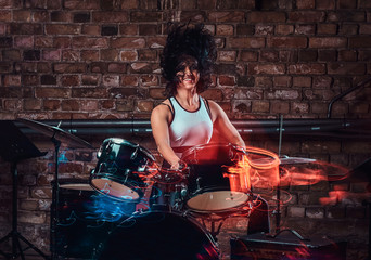 Fototapeta na wymiar Beautiful young girl musician playing on drums and cymbals. Live music in a night club