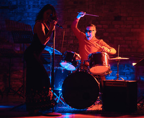 Fototapeta na wymiar Jazz band performance. Young couple of musicians - a drummer and a singer in a nightclub.