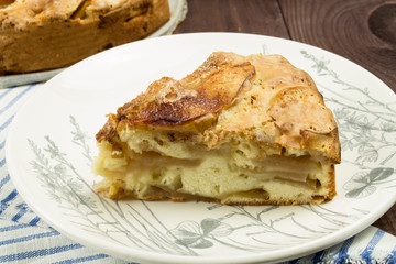 A slice of apple pie cake pie on a white plate, close-up, apples are visible in large slices