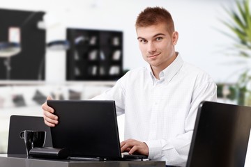 Businessman in office lobby with laptop