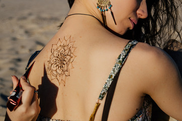 The image of the back of the girl decorated with henna tattoo. Mehndi mandala.