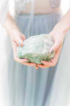 Hands hold large raw green crystal