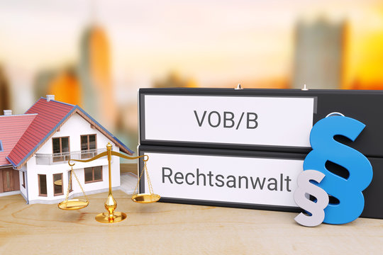 Vergabe- und Vertragsordnung. Ordner beschriftet mit den W&ouml;rtern VOB/B und Rechtsanwalt liegen neben einem Haus, einer Waage sowie Paragrafen-Zeichen auf einem Schreibtisch. Skyline einer Stadt