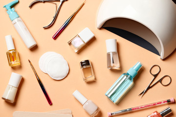 Flat lay composition of Manicure tools, UV lamp and nail polishes on a pink background. Place for text.