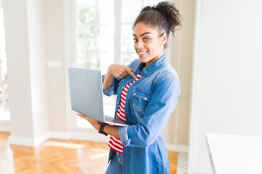 Young african american girl standing working using laptop with surprise face pointing finger to himself