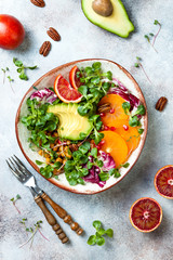 Vegan, detox Buddha bowl with turmeric roasted  chickpeas, greens, avocado, persimmon, blood orange, nuts and pomegranate. Top view, flat lay
