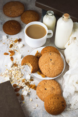 Oatmeal cookies, Books, Oatmeal Flakes, Cup of Coffee with Milk, Raisins on a light background. The concept of Good Morning and Breakfast