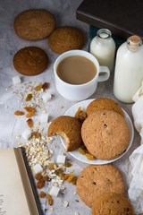 Oatmeal cookies of manual work, Books, Oatmeal Flakes, Cup of Coffee with Milk, Raisins on a light background. Breakfast Concept