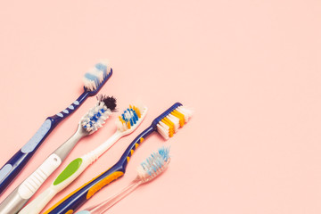 Several different used toothbrushes on a pink background. Toothbrush change concept, oral hygiene, big and friendly family, toothbrush selection. Flat lay, top view.