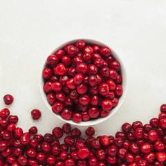 Fresh cherries in a white plate and scattered around on a light stone background. Flat lay, top view