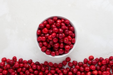 Fresh cherries in a white plate and scattered around on a light stone background. Flat lay, top view