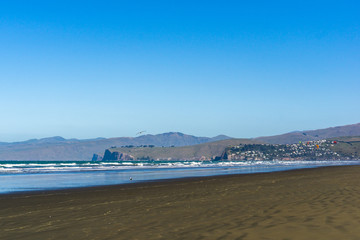 empty vast beach with coastal line and mountains on the horizon line during sunny day
