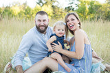 Young family sitting in field smiling