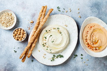 Different homemade hummus bowls. Traditional hummus with thyme, olive oil and pine nuts and roasted...