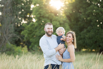 attractive young family standing in field smiling