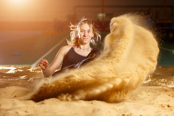 Female long jump athlete landing in sandpit