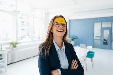 Young businesswoman with yellow sticky note on her forehead, saying 'burnout'