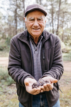 Portrait of smiling senior man showing found mushrooms