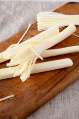 Fototapeta na wymiar String cheese on rustic wooden board, low angle view. Healthy snack. Close-up.