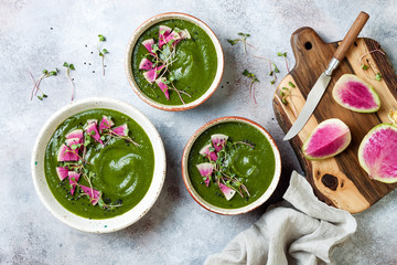 Homemade green spring spinach cream soup decorated with watermelon radish, black sesame seeds and...