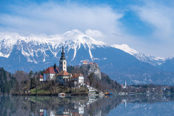 Church Bled on island reflected in lake with mountain-range Karawanks
