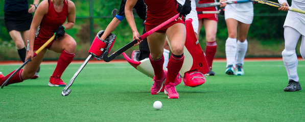 Field hockey players challenge eachother for possession of the ball on the midfield battle of a...