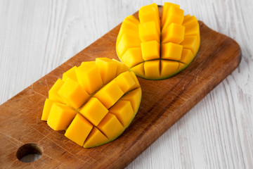 Sweet mango on rustic wooden board over white wooden surface, low angle view. Close-up.