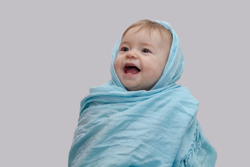 A little girl in a colored scarf on her head, the first milk teeth, a joyful smile, an open mouth