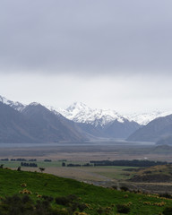 foggy landscape in the mountains, brown hills and peaks covered by snow, road in a vast valley