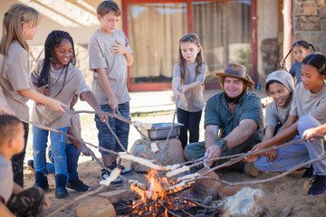 Children and guide roasting twist bread at camp fire