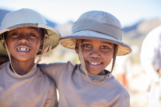 Portrait of two smiling boys embracing wearing pith helmet