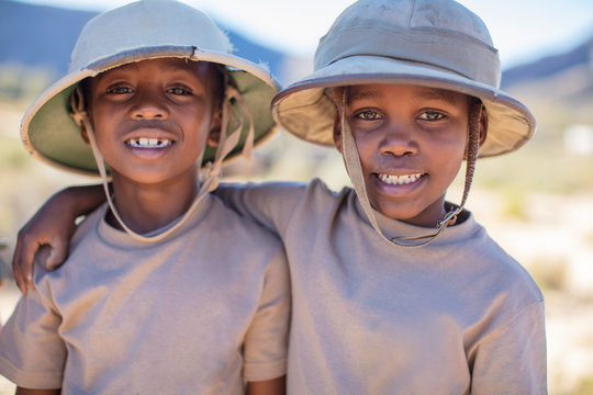 Portrait of two smiling boys embracing wearing pith helmet