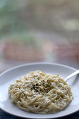 Plate of lemon and cheese pasta, seasoned with basil. Selective focus.