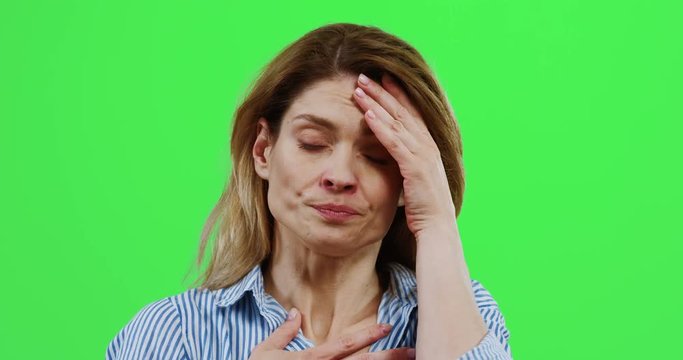 Close up of the Caucasian unhealthy woman caughing and having bad headache on the green screen. Chroma key.
