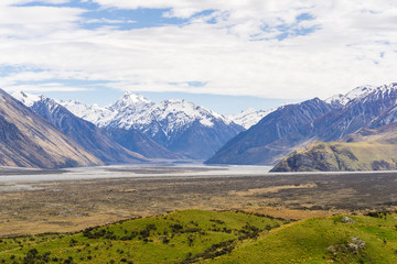 mountain landscape in the mountains, beautiful vast valley with mountains on the horizon, mountain peak covered by snow, during sunny with dramatic sky