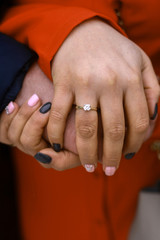 Couple holding hands with a diamond engagement ring 