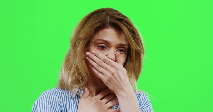 Close up of the Caucasian unhealthy woman having a bad caugh spasm and being on the chroma key wall. Green screen.