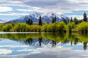 Fototapeta na wymiar Symmetrical landscape due to reflection in a lake, trees and mountain range reflecting in a lake
