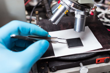 hand with tweezers in blue gloves, taking the chip on the table