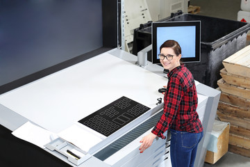 Kobiet obsługuje maszynę drukarską. Komputer sterujący procesem druku. 